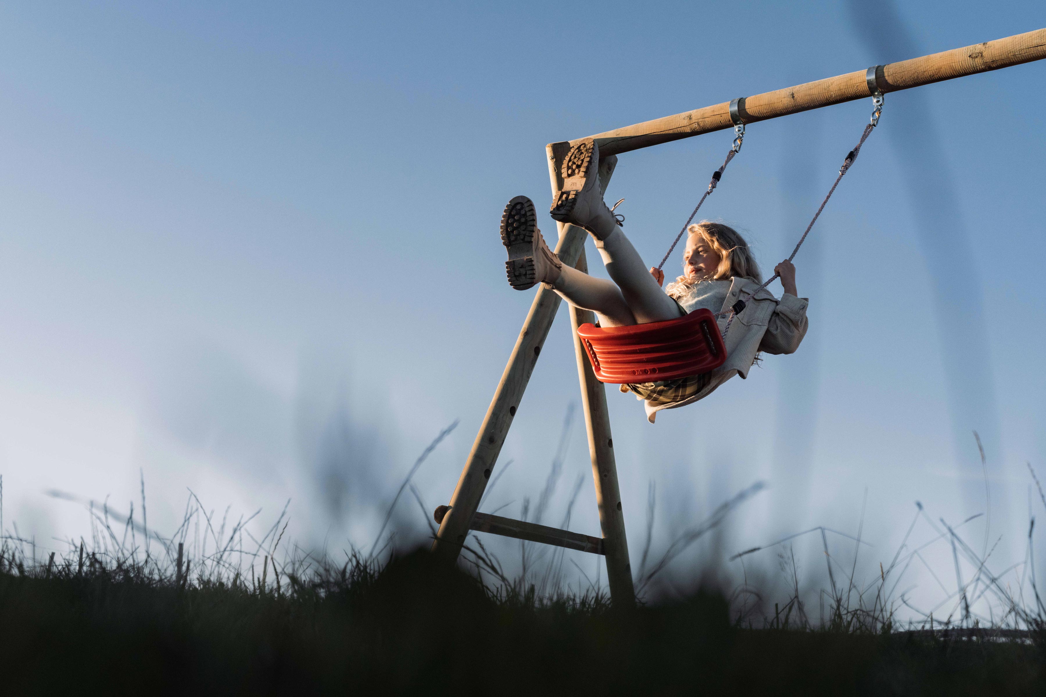 Petite fille blonde sur une balançoire rouge