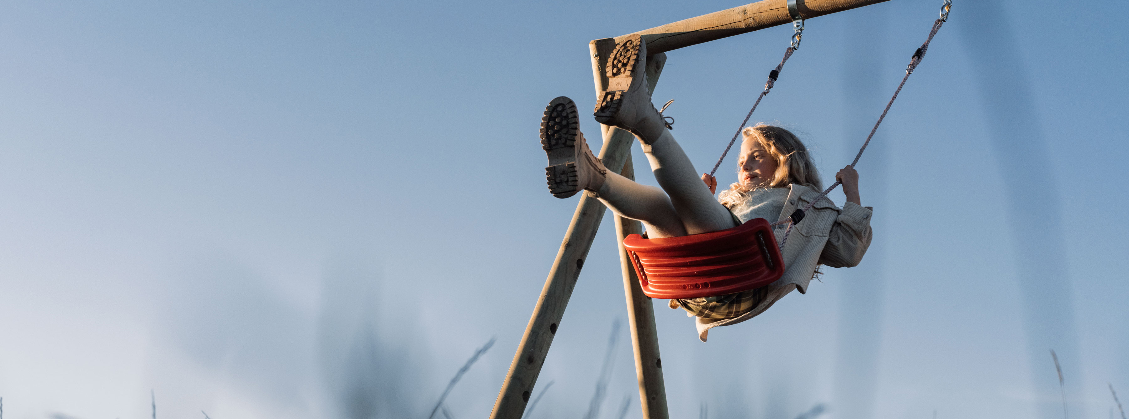 Petite fille blonde sur une balançoire rouge