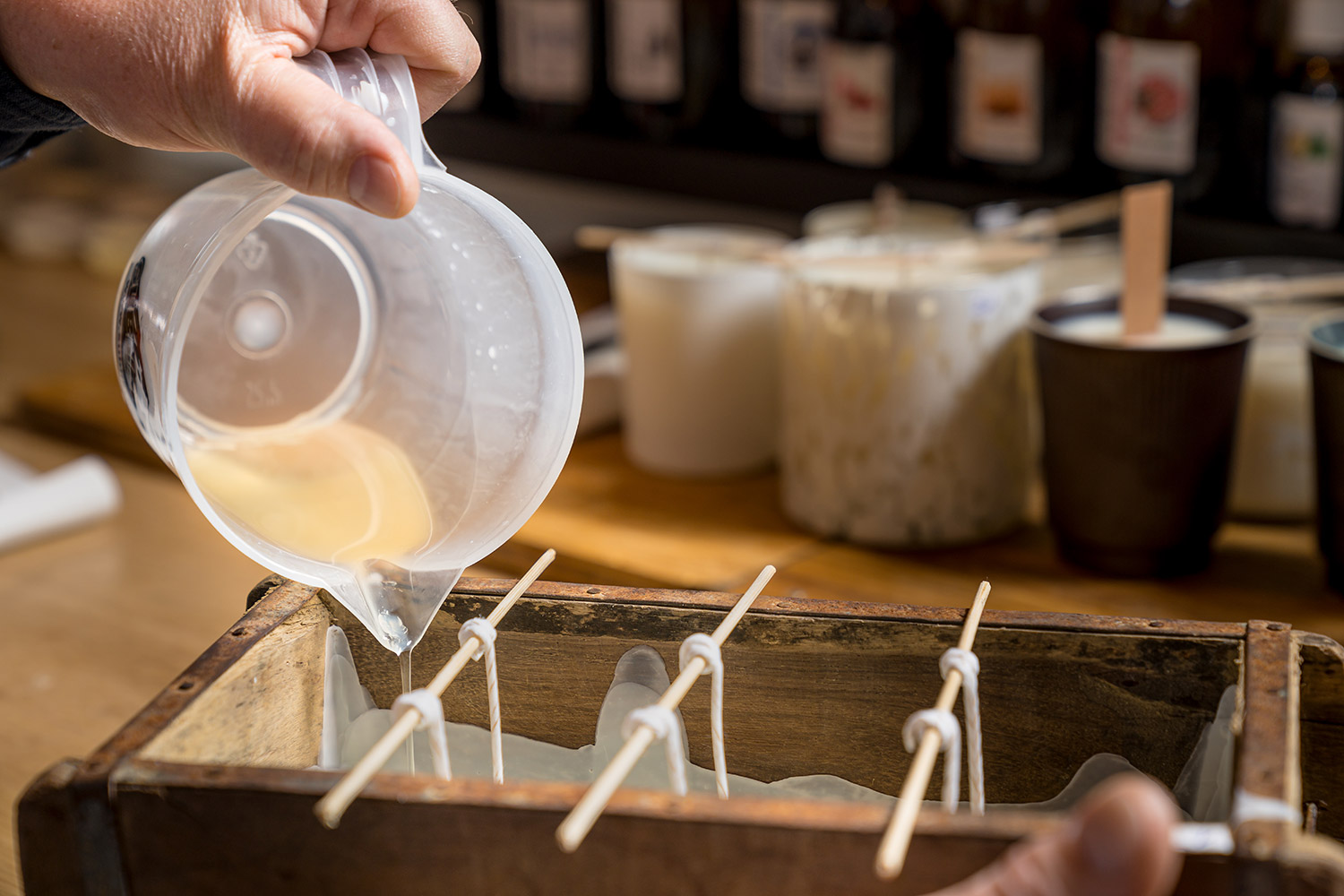 Mains qui coulent la cire pour faire des bougies