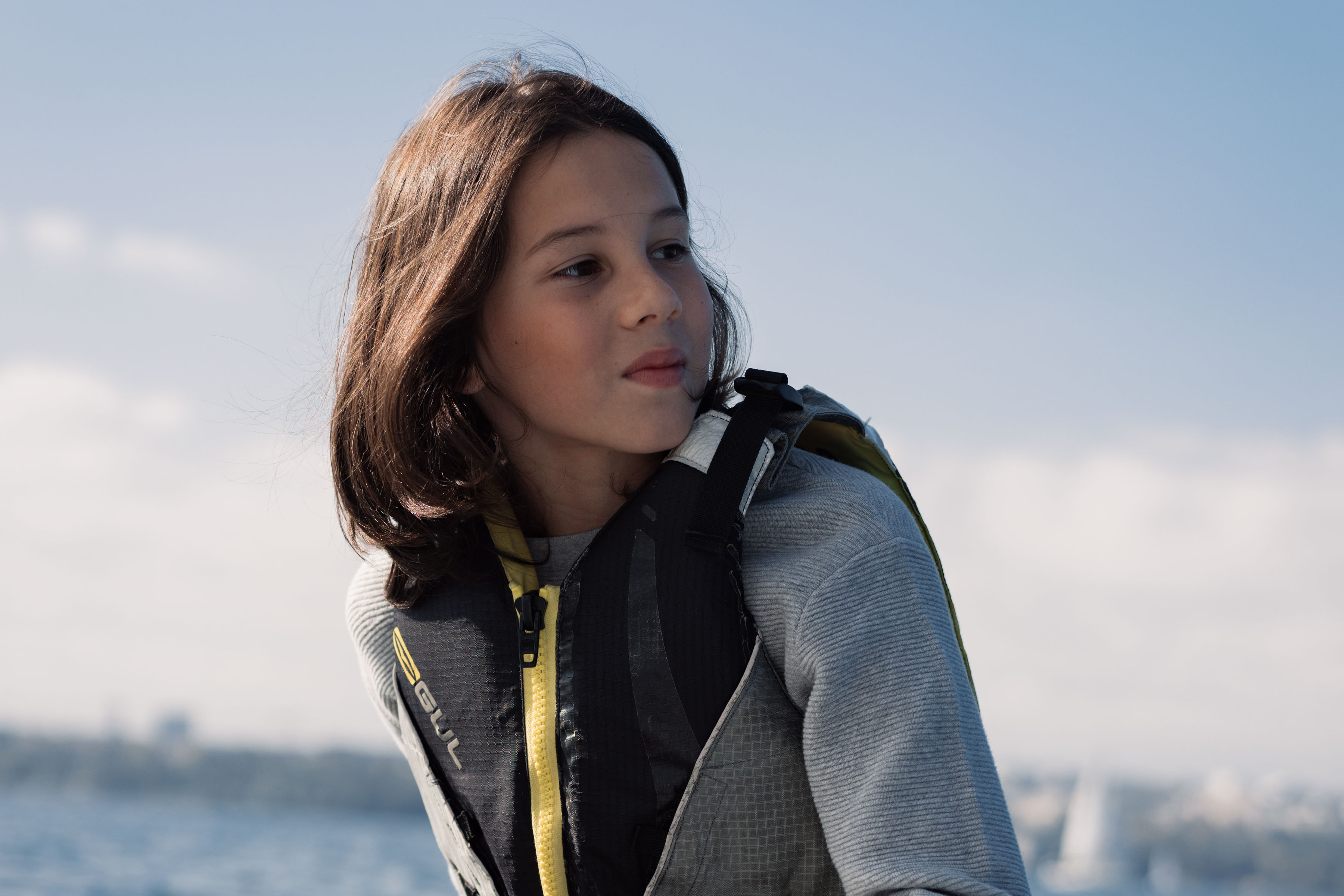 Petit garçon sur un un bateau à voile sous le ciel bleu
