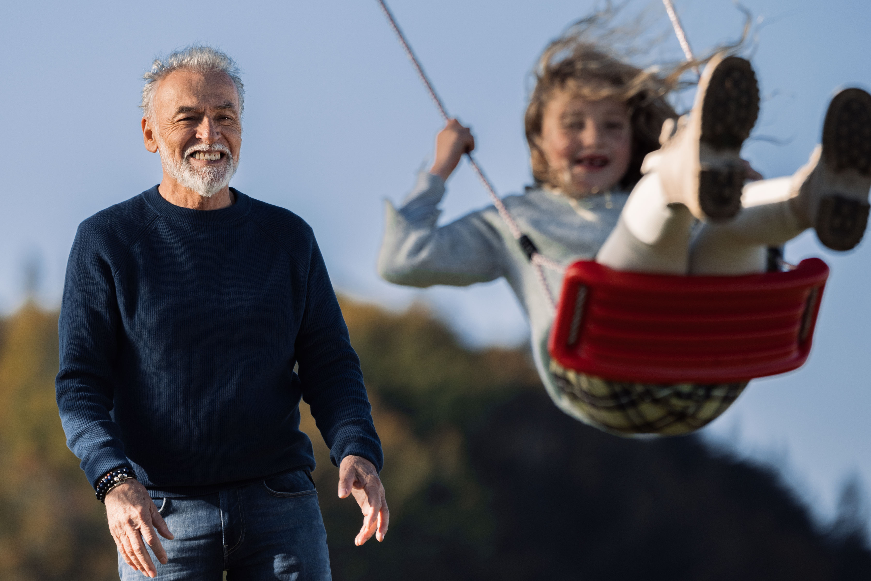 Grand-père qui pousse la balançoire de sa petite fille
